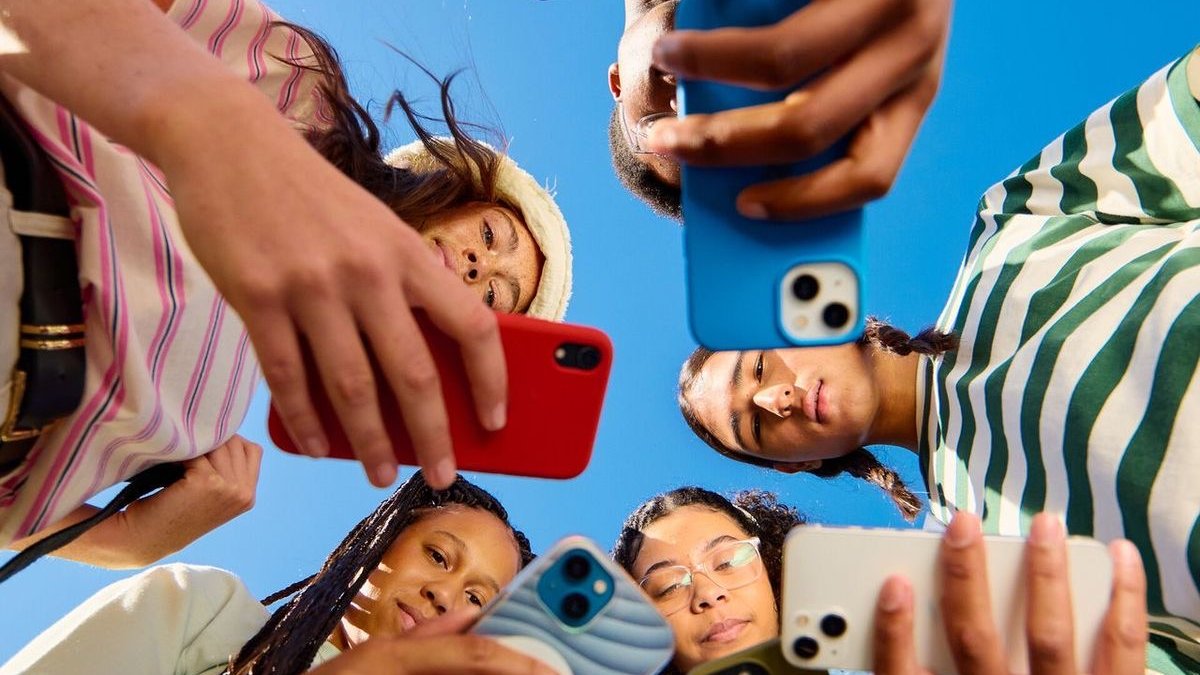 Friends standing in a circle looking down at their phones