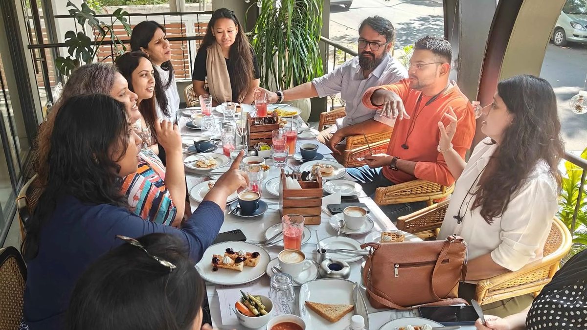 A group of new friends talking over brunch at a long cafe table